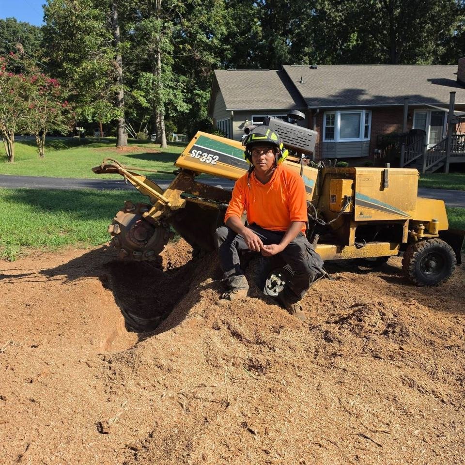 JC Tree Services crew member next to a stump grinder after grinding a stump